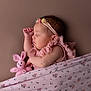 élise a rejoint le concours — aidez-le/la à gagner de superbes lots ! baby, sleeping, pink_outfit, headband, knitted_toy, bunny, blanket, floral_pattern, peaceful, cute, child, portrait, indoors, soft_lighting, newborn, resting, infant, hand, face, cozy