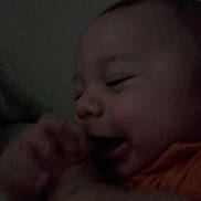 Parker is registered to the contest to win money with this photo: baby, child, face, smile, hand, closeup, infant, portrait, person, happy, dark, indoors, cozy, cute, expression, skin, head, mouth, young, sleepwear
