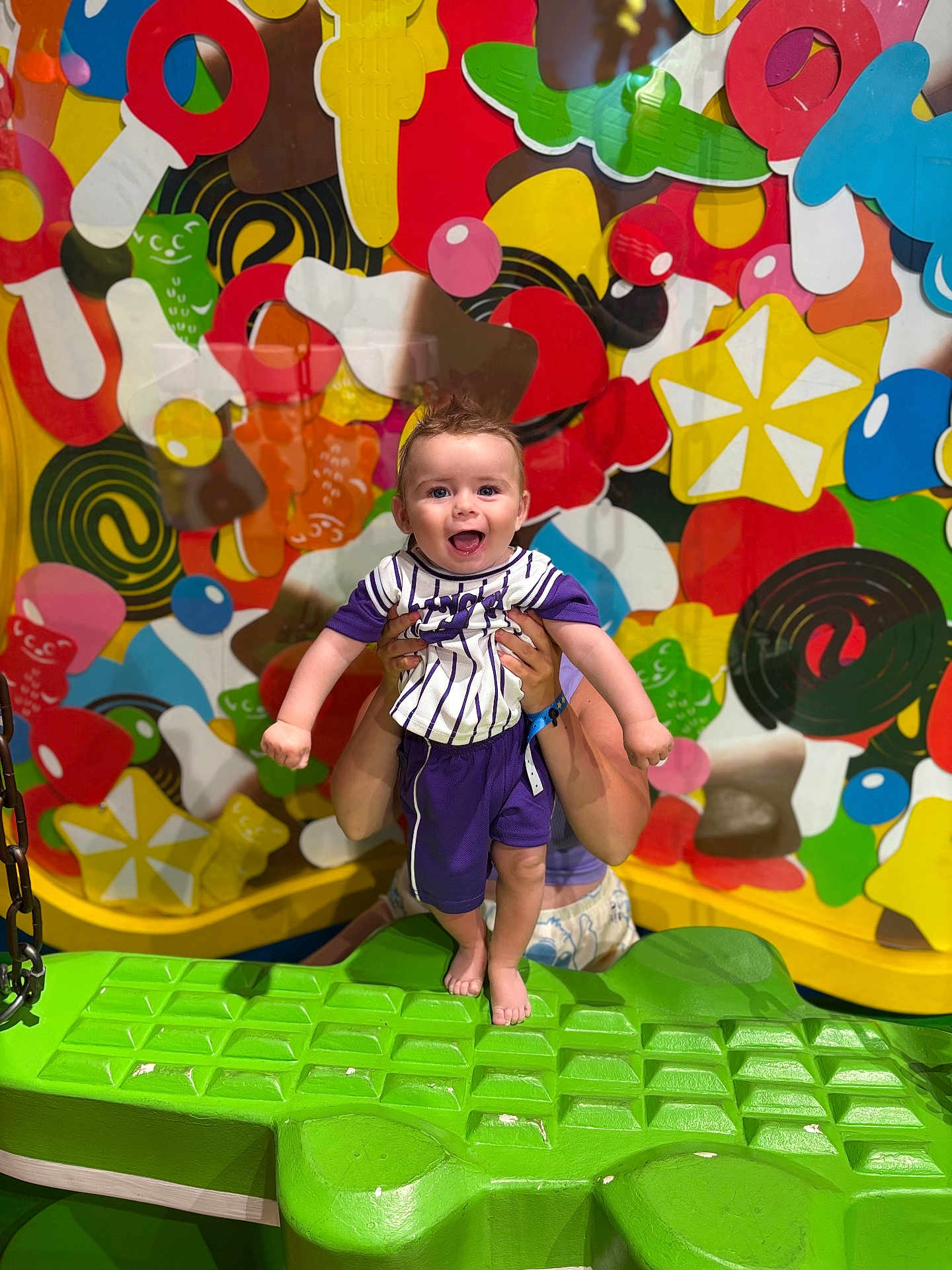 Dawson Tarlet participe au concours pour gagner de l'argent avec cette photo : alligator_seat, baby, bright_colors, cheerful, child, colorful_background, face, feet, fun, hands, happy, holding, indoor, patterned_shirt, person, play, playground, purple_clothing, smiling, toy