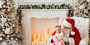 Maizey-May is registered to the contest to win money with this photo: baby, candle, celebration, christmas_tree, decoration, festive, fireplace, floor, gift, holiday, indoor, pacifier, red_clothing, santa_claus, smile, stuffed_toy, wall, white_armchair, winter, wreath