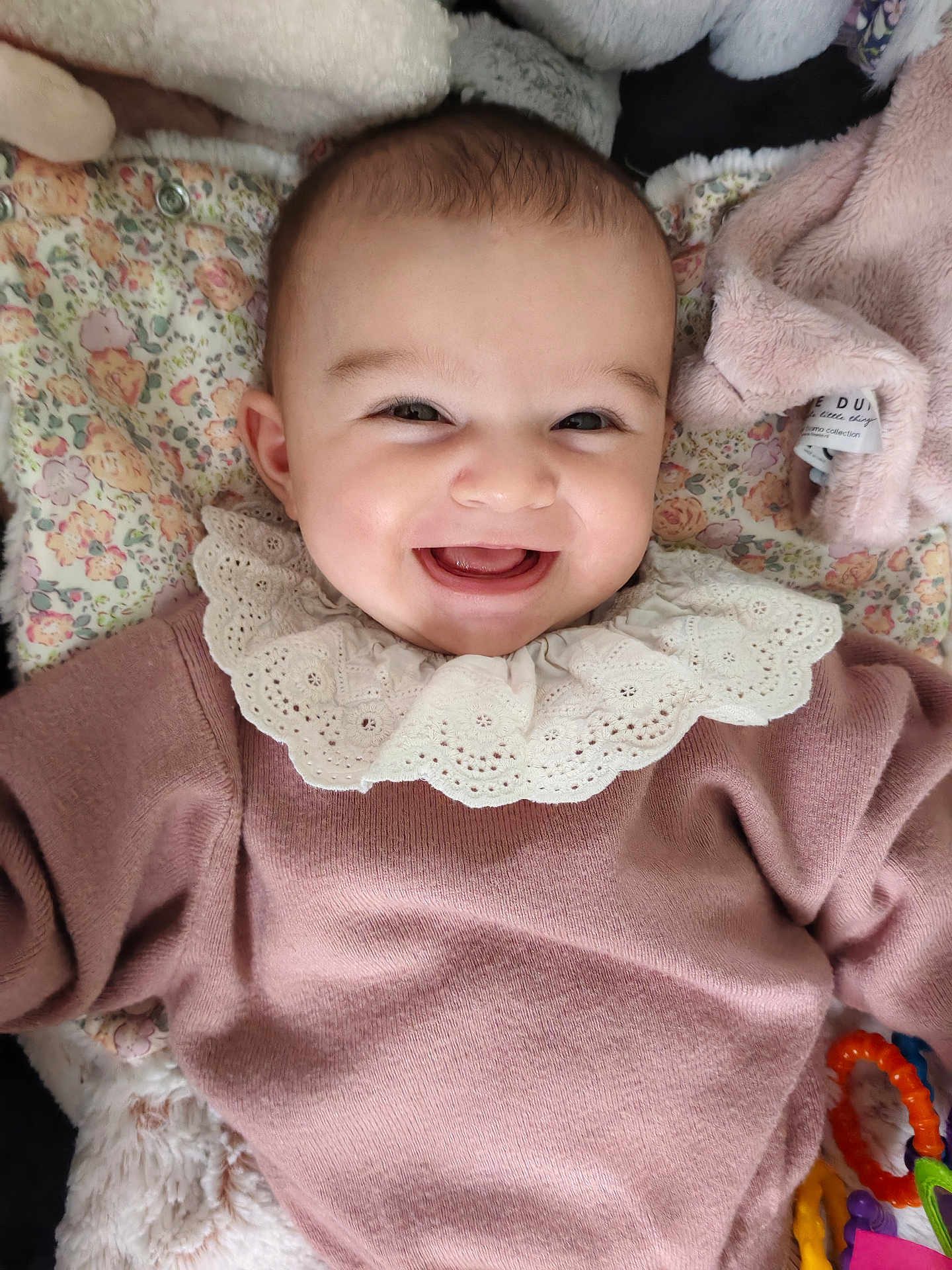 Léa a rejoint le concours — aidez-le/la à gagner de superbes lots ! baby, smile, face, infant, pink_sweater, lace_collar, blanket, floral_pattern, toy, rattle, happy, cute, child, lying_down, soft_toys, indoors, portrait, closeup, warm_clothing, infant_fashion