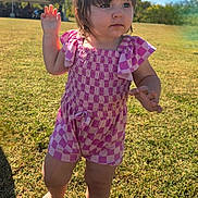 Faye is registered to the contest to win money with this photo: toddler, child, outdoor, grass, sunlight, romper, pink_clothing, walking, baby, daylight, nature, summer, barefoot, cute, portrait, young_child, field, sunny, person, curious