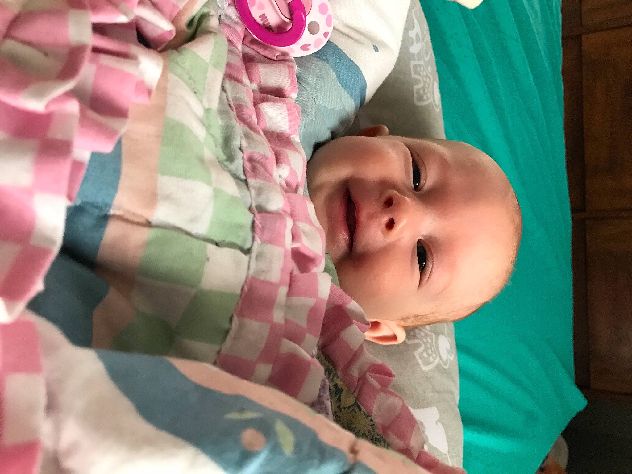 Elana is registered to the contest to win money with this photo: baby, baby_products, baby_toddler_clothing, bed, cheek, child, close_up, comfort, eye, face, facial_expression, head, linens, nose, pattern, person, pink, skin, sleeve, textile