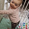 Maria joined the competition — help win amazing prizes! baby, crib, child, smiling, standing, toy, blanket, patterned_clothing, pink_shirt, indoor, floor_tiles, white_bars, play_area, happy, infant, cute, home, baby_gear, colorful_toy, soft_mattress