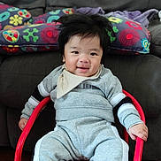 Eiji participe au concours pour gagner de l'argent avec cette photo : baby, child, smiling, indoor, sitting, clothing, bib, socks, chair, red, grey, face, happy, furniture, couch, pillow, patterned, person, cozy, portrait