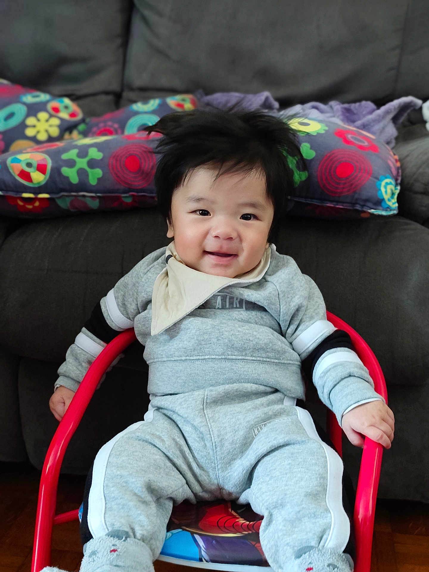 Eiji participe au concours pour gagner de l'argent avec cette photo : baby, child, smiling, indoor, sitting, clothing, bib, socks, chair, red, grey, face, happy, furniture, couch, pillow, patterned, person, cozy, portrait