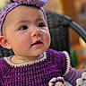 baby, child, purple_clothing, headband, crochet, toy, curious, portrait, indoor, cute, face, expression, infant, colorful, soft_light, sitting, young_child, closeup, smiling, playful