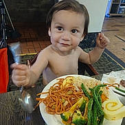 Rey joined the competition — help win amazing prizes! toddler, child, smiling, plate, food, noodles, vegetables, broccoli, green_beans, rice, cake_roll, spoon, table, indoor, restaurant, happy, person, meal, dining, cute