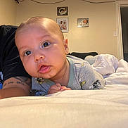 Lorenzo is registered to the contest to win money with this photo: baby, infant, bedroom, bed, blanket, tattoo, person, portrait, indoors, child, family_photos, curious, cute, sleepwear, mickey_mouse, skin, face, expression, adult, tshirt