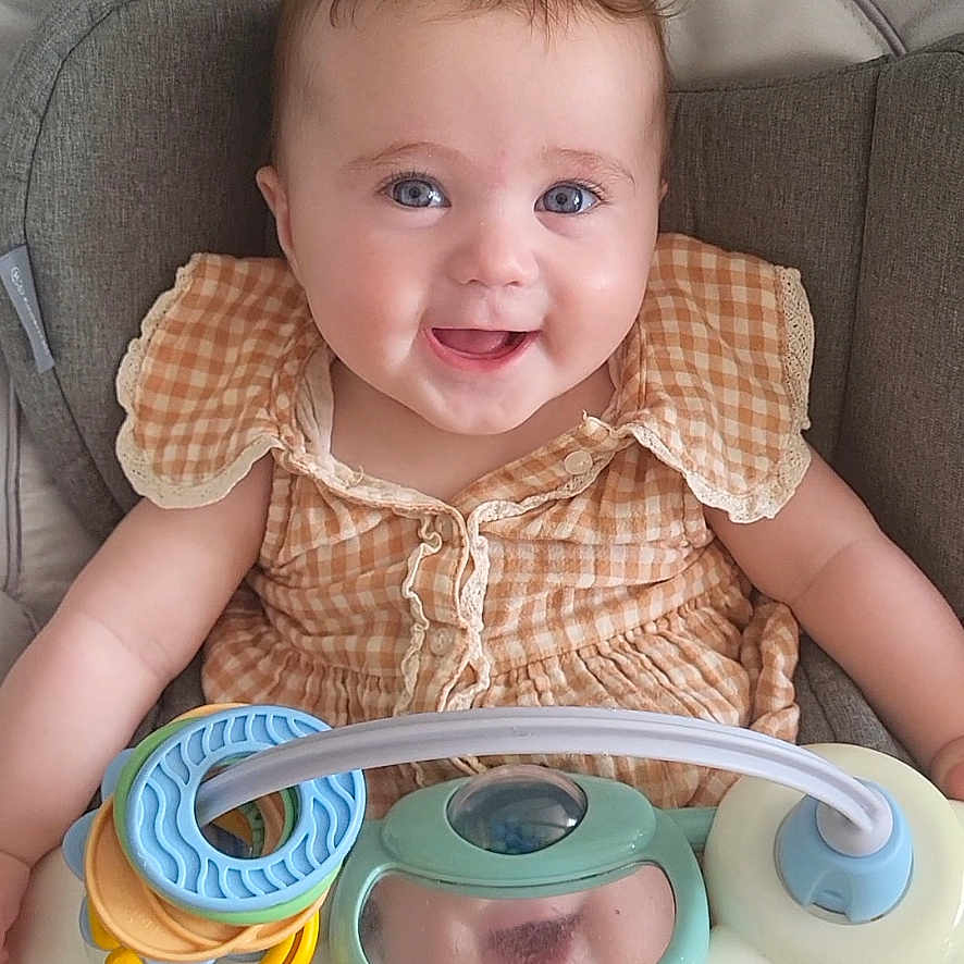 Noéline participe au concours pour gagner de l'argent avec cette photo : baby, baby_seat, blue_eyes, cheerful, child, colorful, cute, gingham_dress, happy, indoors, infant, joy, person, plastic_rings, playtime, portrait, seat, smiling, toy, young_child