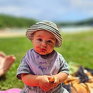 Issam participe au concours pour gagner de l'argent avec cette photo : baby, child, hat, bib, food, messy_face, outdoor, grass, blanket, sunny, summer, sitting, cute, portrait, young_child, clothing, nature, daylight, person, closeup