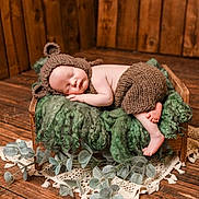 Hugo joined the competition — help win amazing prizes! baby, sleeping, knitted_hat, knitted_pants, wooden_bed, green_blanket, fluffy_texture, rustic, wooden_floor, wooden_wall, eucalyptus_leaves, lace_doily, peaceful, infant, cute, cozy, portrait, indoors, newborn, soft_lighting