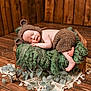 baby, sleeping, knitted_hat, knitted_pants, wooden_bed, green_blanket, fluffy_texture, rustic, wooden_floor, wooden_wall, eucalyptus_leaves, lace_doily, peaceful, infant, cute, cozy, portrait, indoors, newborn, soft_lighting