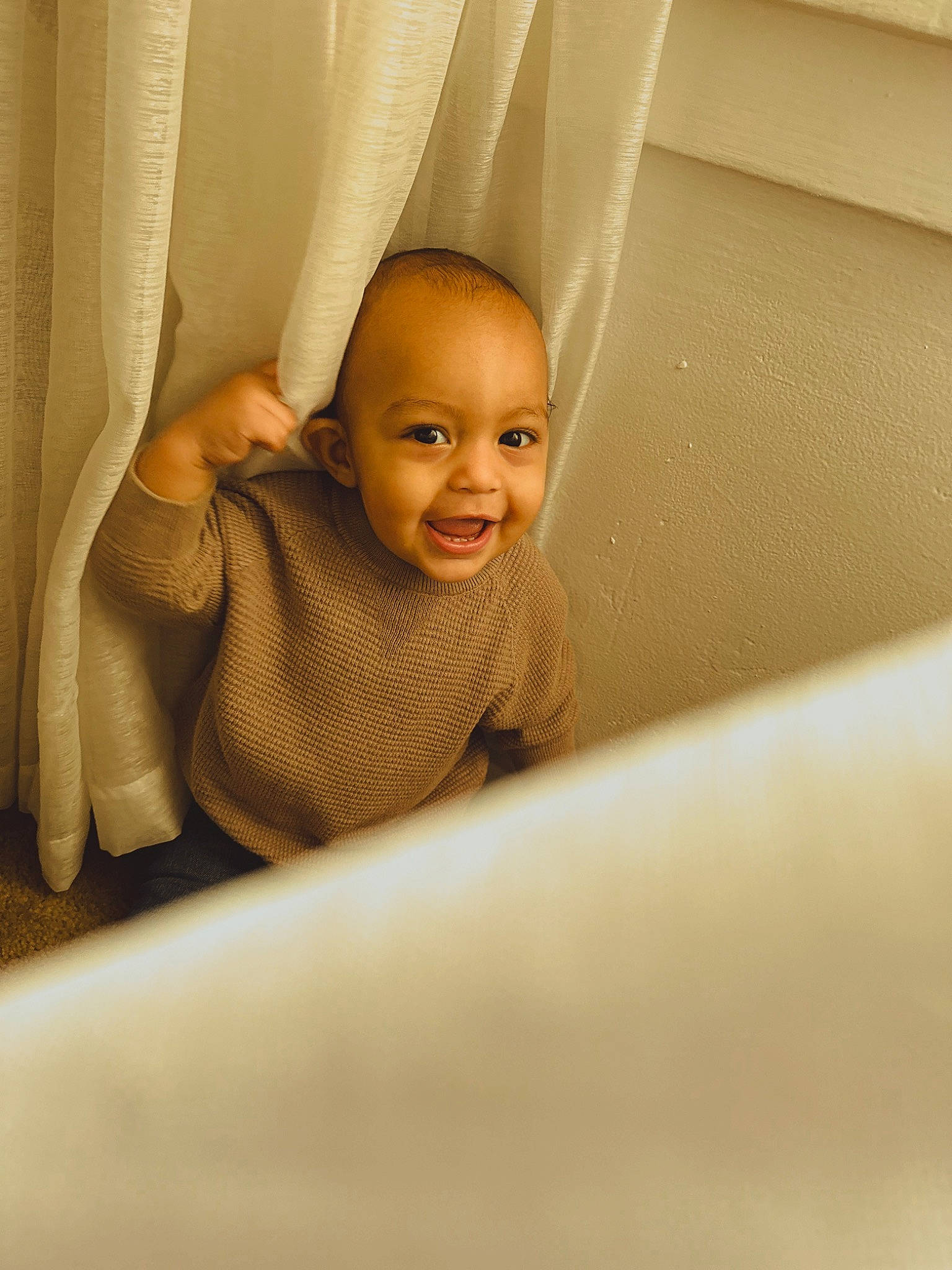 Colson is registered to the contest to win money with this photo: baby, ceiling, comfort, eye, eyebrow, finger, flash_photography, floor, flooring, fun, happy, hardwood, human_leg, mouth, person, room, smile, thumb, tints_and_shades, toddler