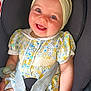 baby, child, car_seat, smiling, headband, bow, floral_dress, pacifier, doll, seatbelt, happy, cute, infant, portrait, sitting, indoors, person, baby_toy, clothing, face