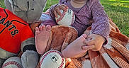 Ava joined the competition — help win amazing prizes! baby, infant, child, smiling, outdoor, park, baseball, sports, plush_toy, dog_toy, blanket, pink_headband, pink_clothing, sitting, bare_feet, green_grass, trees, sunlight, portrait, happy