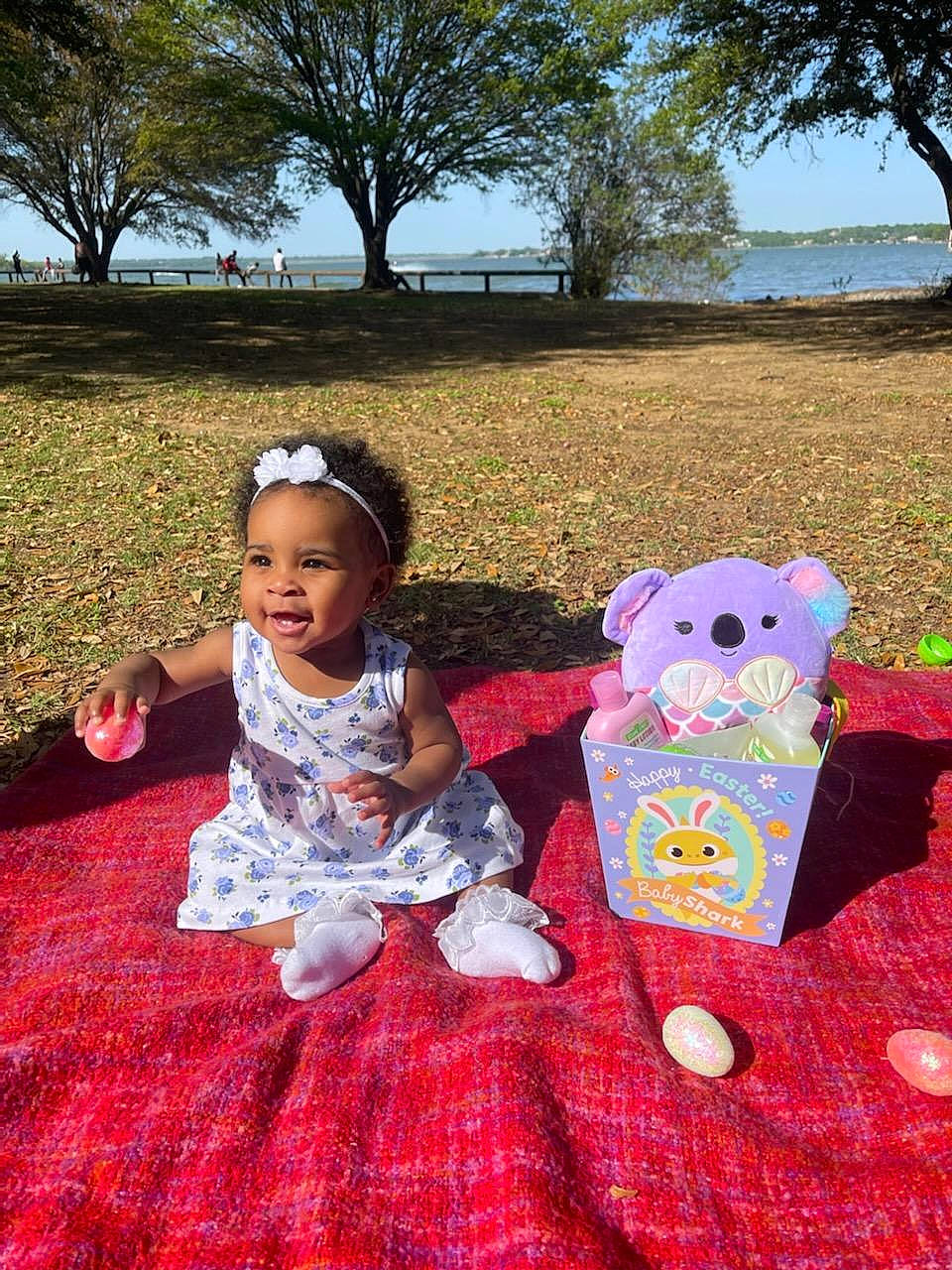 Blake is registered to the contest to win money with this photo: baby, baby_toddler_clothing, bag, child, flooring, fun, grass, happy, leisure, magenta, person, pink, plant, recreation, sky, smile, stuffed_toy, toddler, toy, tree