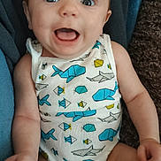 Rhyatt joined the competition — help win amazing prizes! baby, infant, onesie, fish_pattern, blue, yellow, smiling, happy, child, cute, sitting, indoors, blanket, skin, face, arms, legs, apparel, comfort, expression