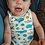 baby, infant, onesie, fish_pattern, blue, yellow, smiling, happy, child, cute, sitting, indoors, blanket, skin, face, arms, legs, apparel, comfort, expression