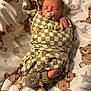 baby, bear_motif, bed, blanket, checkered_pattern, cozy, cute, fabric_texture, hands_near_face, infant, knitted_booties, newborn, nursery_bedding, pacifier, portrait, sleeping, soft_lighting, swaddle, teddy_bear_print, wooden_beads