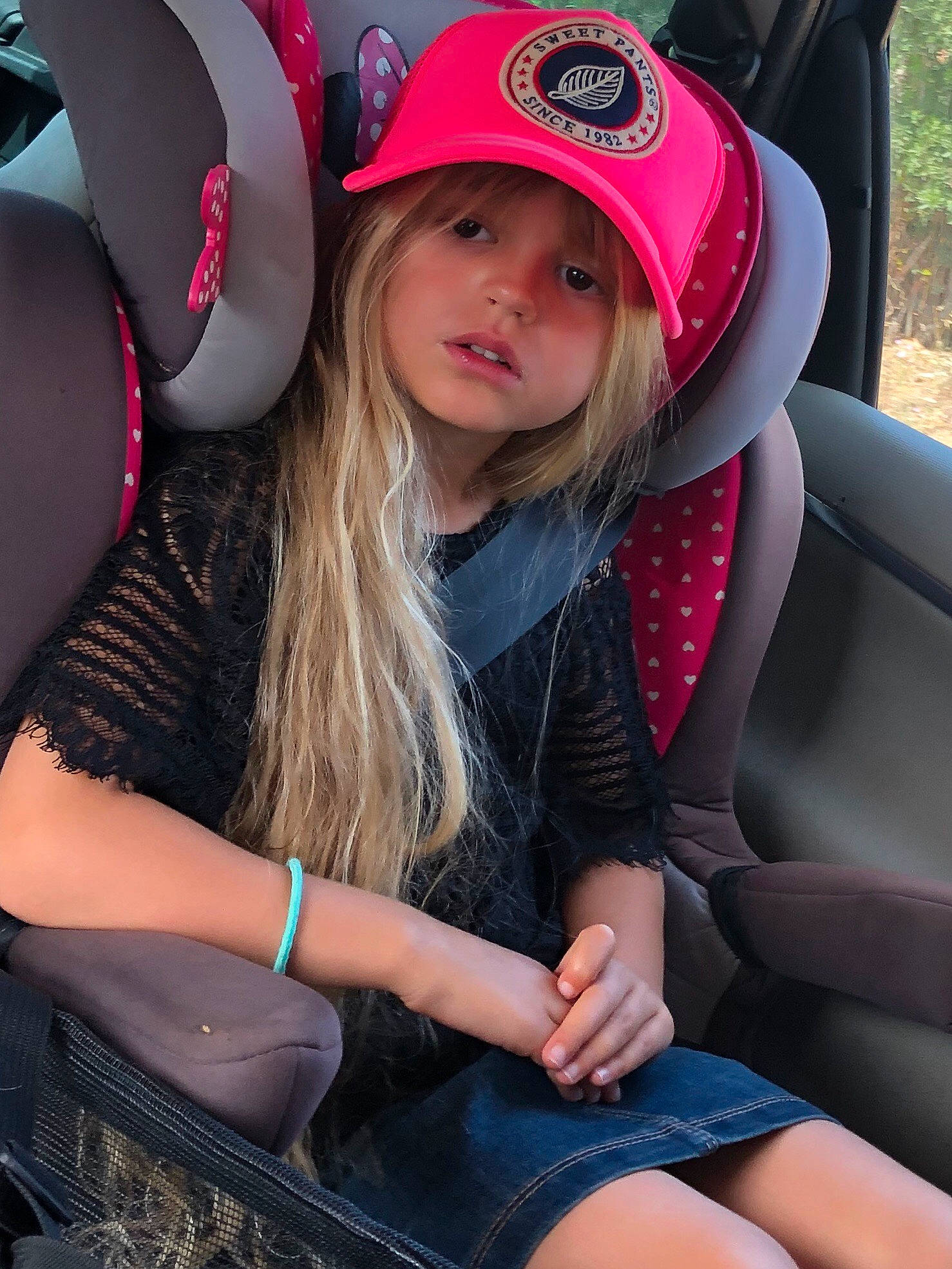 Myla participe au concours pour gagner de l'argent avec cette photo : auto_part, car_seat, car_seat_cover, finger, headwear, leg, person, pink, seat_belt, steering_wheel, thigh
