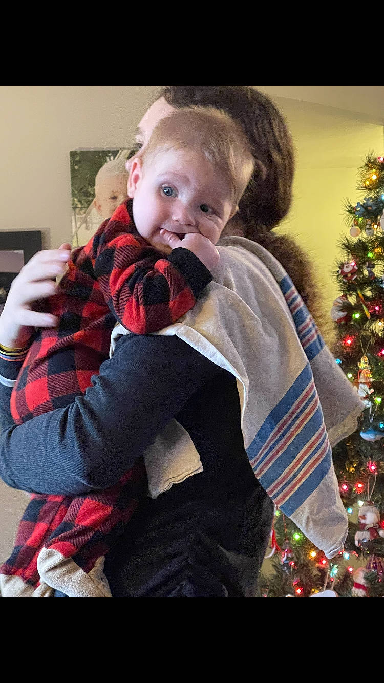 Jason is registered to the contest to win money with this photo: baby, baby_toddler_clothing, child, christmas_tree, comfort, event, facial_expression, fun, gesture, happy, human, iris, lap, outerwear, person, plaid, sitting, sleeve, smile, standing