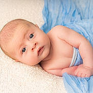 Freddie is registered to the contest to win money with this photo: baby, infant, blue_cloth, blanket, lying_down, skin, face, eyes, expression, cute, newborn, child, soft_texture, hand, portrait, closeup, sleepwear, resting, indoors, peaceful
