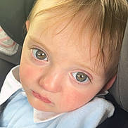 Rían Colby joined the competition — help win amazing prizes! baby, child, face, eyes, car_seat, seatbelt, blanket, infant, portrait, closeup, young_child, clothing, expression, indoors, seat, head, skin, hair, sitting, person