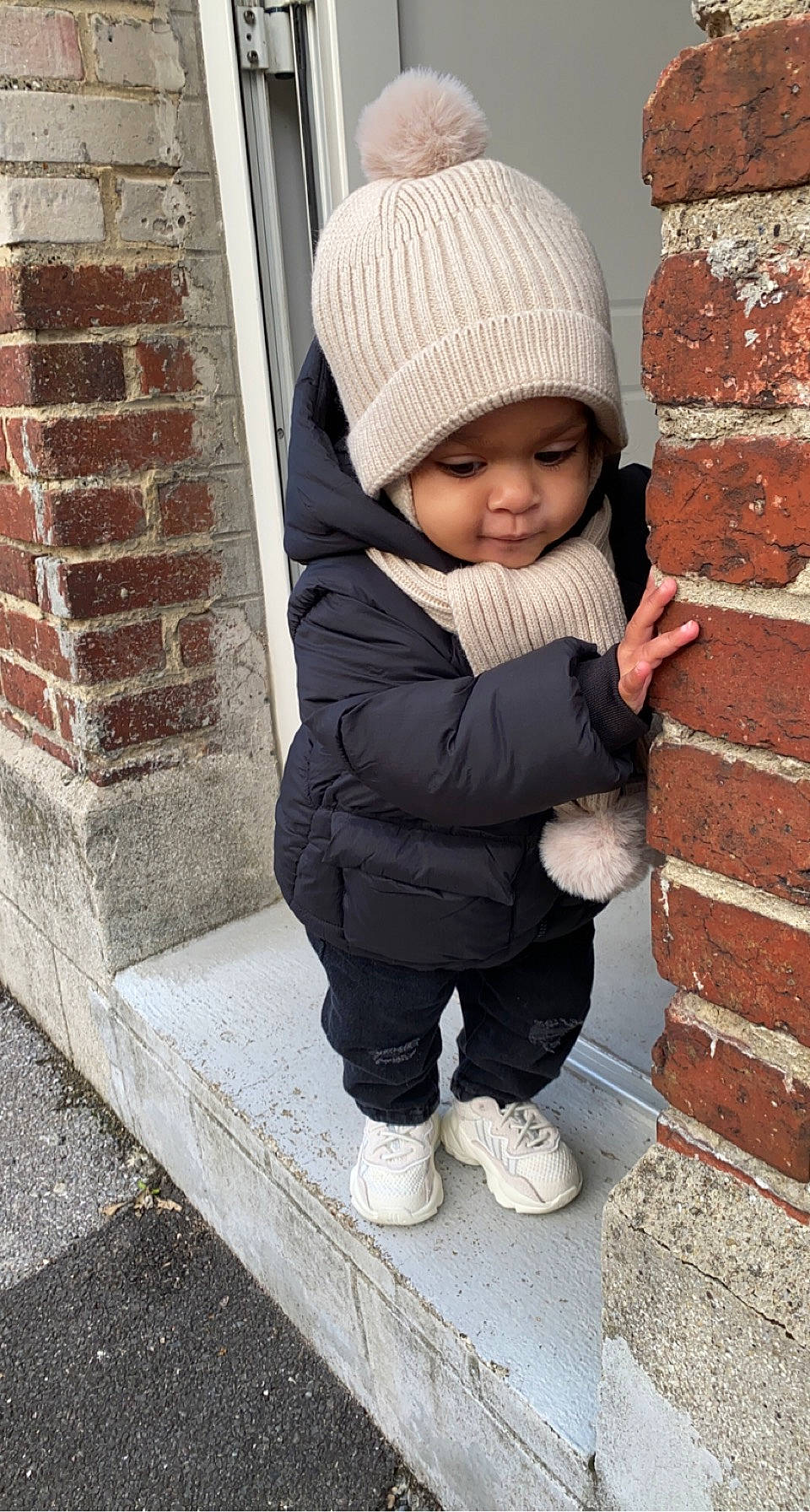 Kamyliah participe au concours pour gagner de l'argent avec cette photo : baby, baby_toddler_clothing, beanie, brick, brickwork, cap, child, clothing, comfort, flooring, headwear, jacket, knit_cap, leg, outerwear, person, sitting, sleeve, toddler, winter