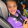 Amiyah is registered to the contest to win money with this photo: child, smile, car_seat, curly_hair, bow, purple_shirt, seatbelt, car_interior, happy, young_girl, portrait, sitting, safety, travel, vehicle, seat, face, hand, clothing, cute