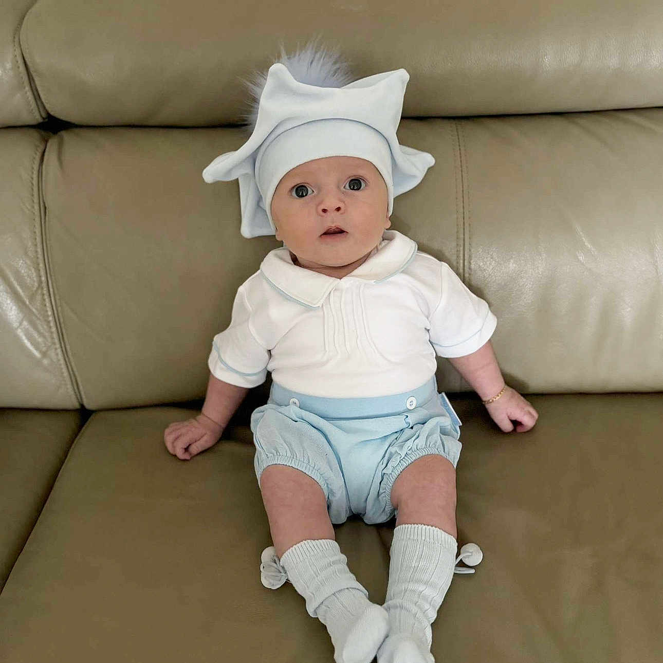 Reaves is registered to the contest to win money with this photo: adorable, baby, blue_clothing, casual, child, couch, cute, expression, furniture, hat, indoor, infant, leather, pom_pom, portrait, sitting, socks, white_clothing, wide_eyes, young