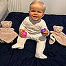 baby, ball, bedspread, blanket, child, cute, furniture, happy, indoors, infant, onesie, person, quilt, radiator, sitting, smiling, soft_toy, teddy_bear, toy, window