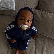 Ohayo participe au concours pour gagner de l'argent avec cette photo : baby, casual, child, clothing, comfort, couch, curious, cute, expression, face, foot, home, hoodie, indoor, pacifier, person, relaxed, sitting, tracksuit, young