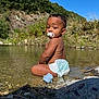 baby, child, curious, cute, diaper, greenery, nature, outdoor, pacifier, play, portrait, river, rocks, shallow_water, sitting, sky, summer, sunlight, water, young_child