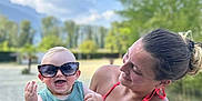 Eddy a rejoint le concours — aidez-le/la à gagner de superbes lots ! baby, blue_sky, casual_clothing, child, daylight, fun, happy, holding, nature, outdoor, person, portrait, smile, summer, sunglasses, sunny, tattoo, trees, woman, wristband