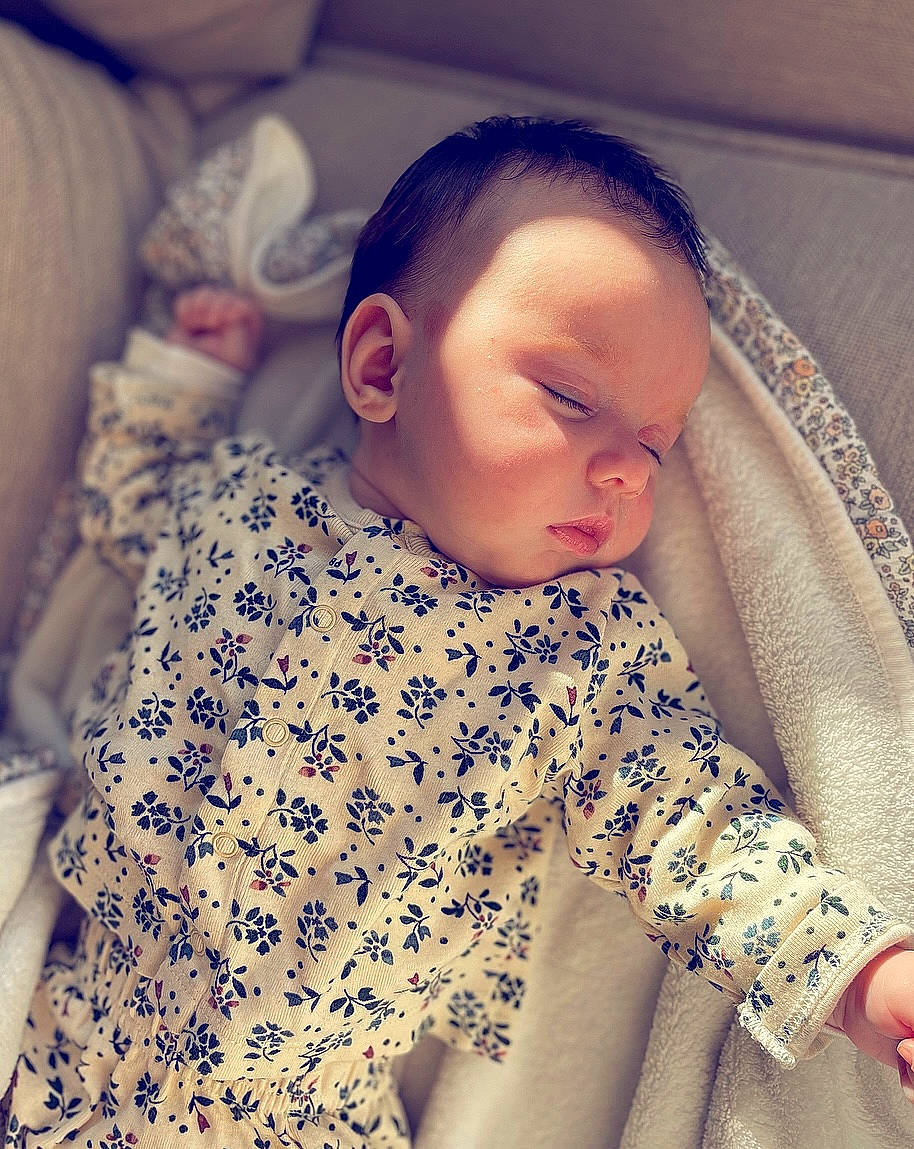Hanaë participe au concours pour gagner de l'argent avec cette photo : arm, baby, baby_sleeping, baby_toddler_clothing, cloud, comfort, eyebrow, face, hair, hand, happy, head, lip, mouth, neck, nose, outerwear, person, skin, sleeve