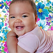 Anna-Maria participe au concours pour gagner de l'argent avec cette photo : arm, baby, bright, cheeks, child, colorful, cute, eyes, face, floral_background, happy, infant, joy, lying_down, mouth, pink_clothing, portrait, skin, smiling, soft_skin