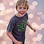 background, blond_hair, blue_eyes, bokeh, boy, casual_clothing, child, cute, expression, happy, joyful, lights, motion, outdoor, portrait, short_sleeves, smiling, standing, tshirt, youth