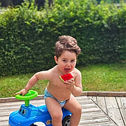 Adam a rejoint le concours — aidez-le/la à gagner de superbes lots ! toddler, child, diaper, toy_car, watermelon, outdoor, grass, hedge, summer, barefoot, play, cute, fun, greenery, wooden_deck, happy, food, fruit, sitting, nature