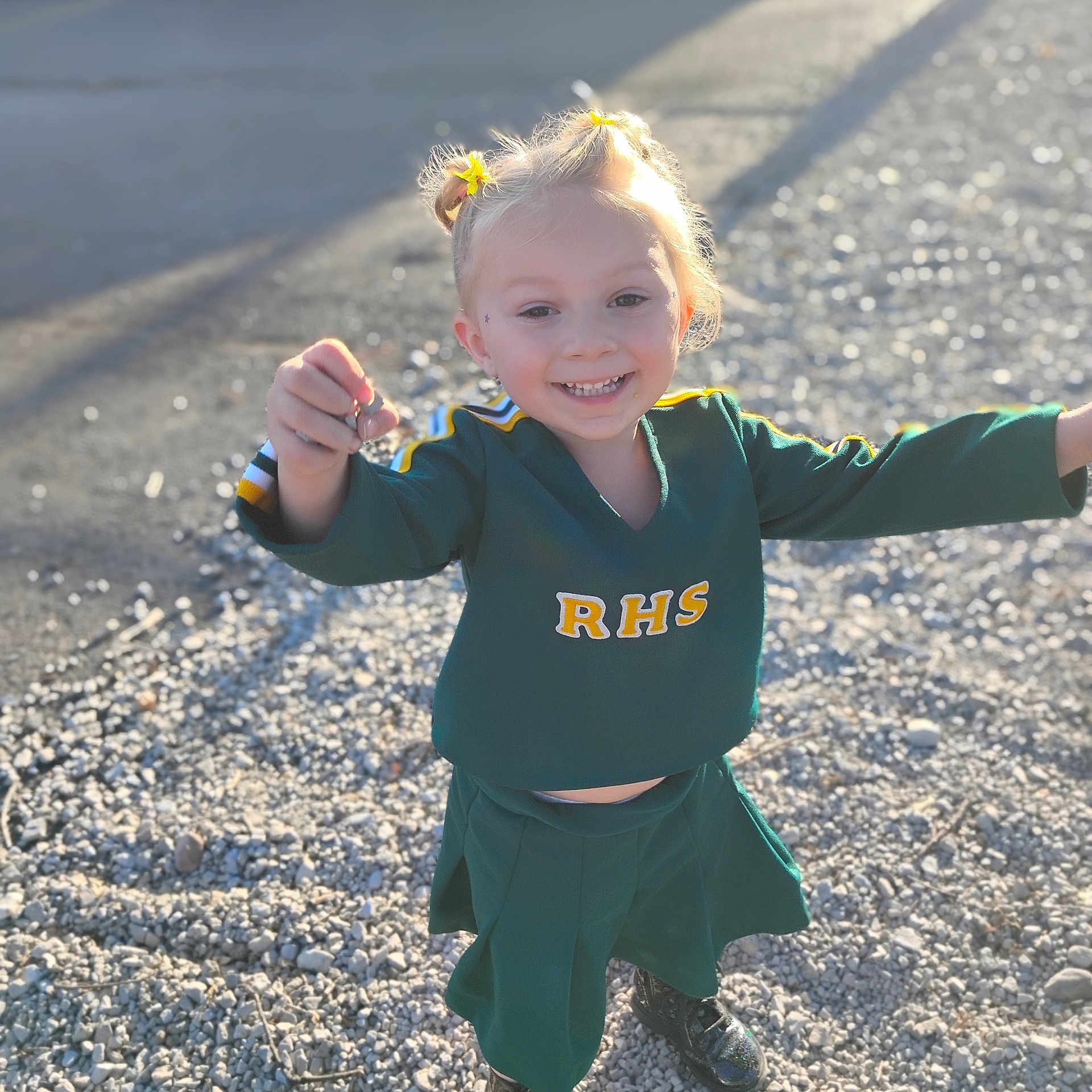 Drailee is registered to the contest to win money with this photo: casual, cheerleader, child, cute, daylight, girl, gravel, green_uniform, happy, joyful, outdoor, person, pigtails, playful, pose, shoes, short_hair, smiling, sunlight, yellow_hair_accessories