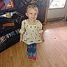 blouse, butterfly_pattern, casual_clothing, child, dvd_shelf, furniture, girl, hair, happy, indoor, jeans, light, nickelodeon, person, pink_shoes, smile, standing, tv, wooden_floor, young