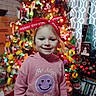 celebration, child, christmas_lights, christmas_tree, colorful, decorations, face, festive, happy, holiday, indoors, person, pink_hoodie, portrait, red_bow, seasonal, smile, smiley_face, smiling, young_child