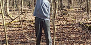 Ryder is registered to the contest to win money with this photo: child, hoodie, sweatpants, tree_stump, forest, leaf_litter, peace_sign, outdoor, nature, sunlight, trees, standing, casual_clothing, young_person, autumn, bare_trees, calm, daytime, woodland, pose
