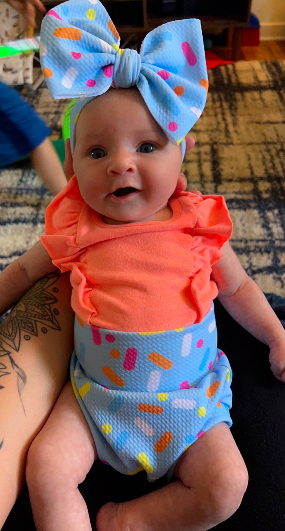 Nora is registered to the contest to win money with this photo: azure, baby, baby_toddler_clothing, blue, cap, face, facial_expression, green, happy, hat, headwear, orange, organ, person, photograph, pink, skin, sleeve, smile, textile