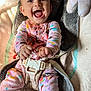 baby, child, smiling, happy, pajamas, colorful_clothing, cushion, seat, harness, baby_seat, infant, playful, indoor, face, hands, feet, closeup, joy, cute, messy