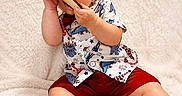 Alistair Thatcher is registered to the contest to win money with this photo: baby, blond_hair, child, closeup, colorful_clothing, curious, indoor, patterned_shirt, photography, playful, polka_dots, portrait, red_shorts, shoe, sitting, smiling, sneakers, soft_blanket, toddler, wide_eyes