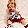 Alistair Thatcher is registered to the contest to win money with this photo: baby, child, toddler, portrait, sitting, wide_eyes, curious, playful, smiling, blond_hair, colorful_clothing, red_shorts, patterned_shirt, sneakers, polka_dots, shoe, indoor, soft_blanket, closeup, photography