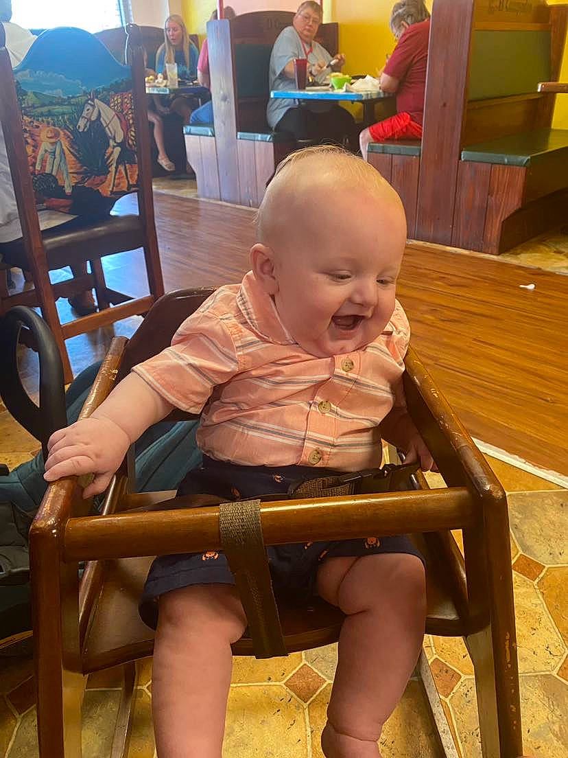 Mavryk is registered to the contest to win money with this photo: baby, baby_toddler_clothing, chair, child, comfort, flooring, foot, fun, furniture, hardwood, human_leg, lap, leisure, person, room, shorts, sitting, thigh, toddler, wood