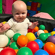 Isla-Mae is registered to the contest to win money with this photo: baby, child, ball_pit, colorful_balls, play_area, indoor, padded_walls, smiling, happy, fun, toys, playtime, infant, cute, person, head, face, clothing, early_childhood, recreation