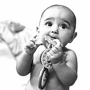 Leilia is registered to the contest to win money with this photo: baby, infant, child, toy, chewing, black_and_white, portrait, curious, expression, close_up, hands, diaper, cute, young, candid, indoor, face, head, skin, playful